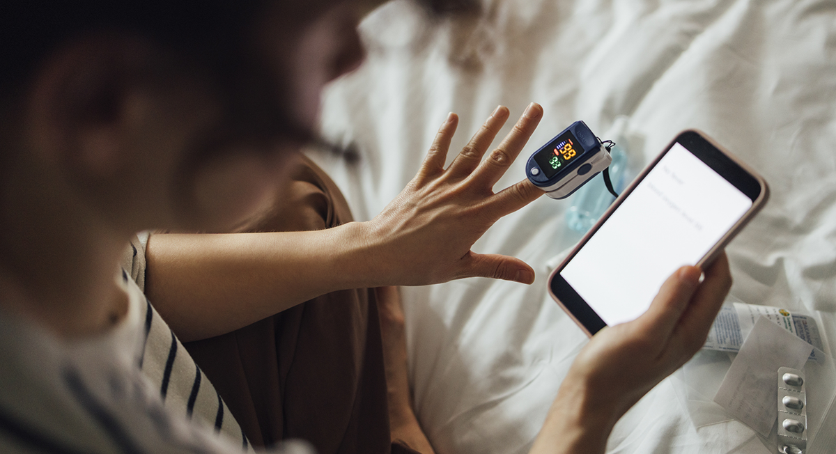 A women using an oximeter while looking at her phone