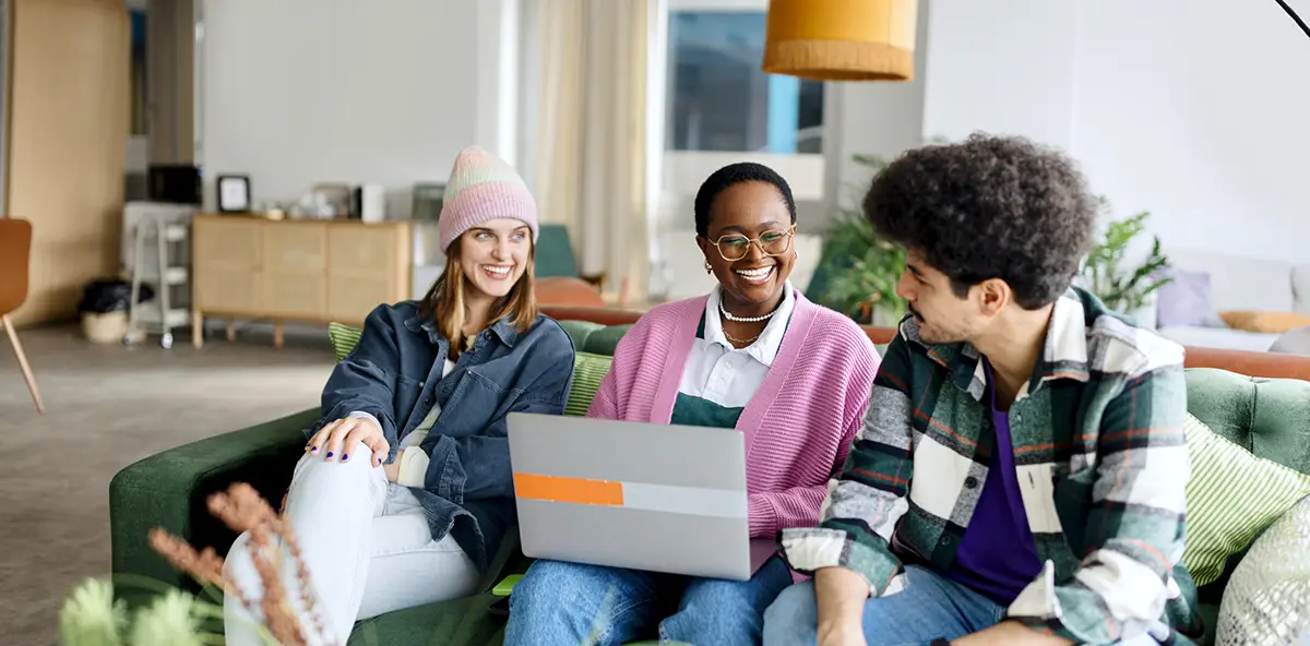 A group of young multiracial people sitting on a sofa chatting and laughing together