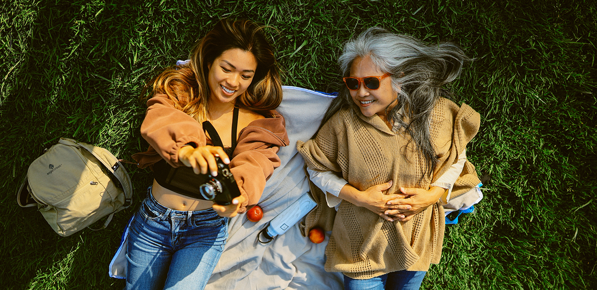 Mom and daughter on a trip in nature together, lying on a picnic blanket