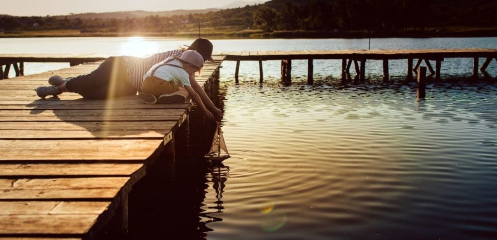 William Russell Global Life Insurance - Banner Image - sunset with parent and child playing with toy boat on lake 3